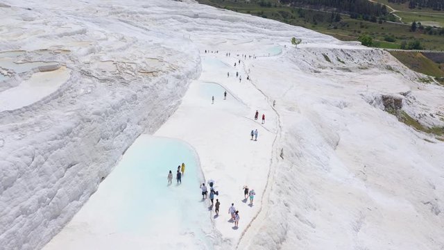 Aerial footage of Pamukkale, Turkey. Tourists walk near artificial travertines. Overall plan 4k