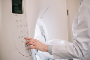 cropped view of radiologist operating mri machine while patient lying on mri scanner bed