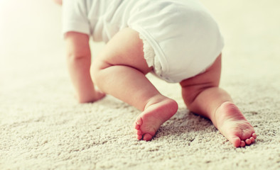 childhood, babyhood and people concept - little baby boy or girl crawling on floor at home
