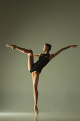 Graceful ballet dancer or classic ballerina dancing isolated on grey studio background. Showing...
