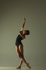 Graceful ballet dancer or classic ballerina dancing isolated on grey studio background. Showing flexibility and grace. The dance, artist, contemporary, movement, action and motion concept. © master1305