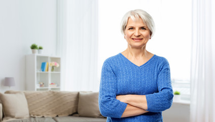 old people concept - portrait of confident smiling senior woman in blue sweater with crossed arms...
