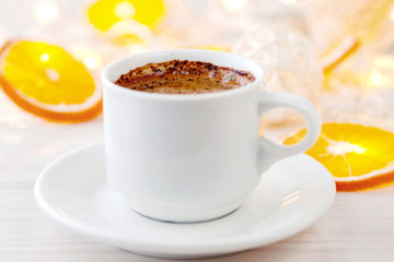 Romantic breakfast. A cup of black coffee and orange slices on a background of glowing lanterns. Postcard Design