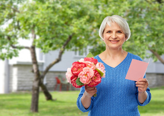 holidays, old age and international women's day concept - happy smiling senior woman with flowers...