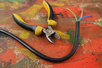 Electrical wire with conductors and electrical pliers on an abstract background