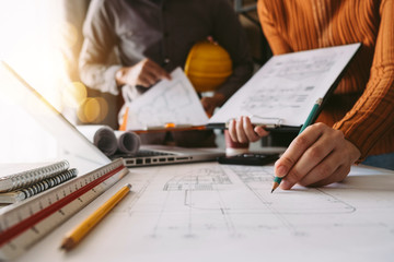 Two colleagues discussing data working and tablet, laptop with on on architectural project at construction site at desk in office