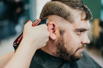 Fototapeta premium beautiful girl hairdresser cuts a bearded man in the salon