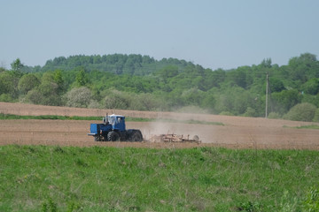 Fototapeta premium Agriculture. The tractor with a plow plough the ground.