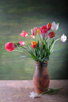 Bouquet of tulips in a clay vase on the table.