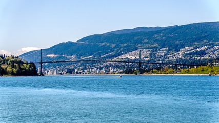 Fototapeta na wymiar View of the Lions Gate Bridge, a suspension bridge that connects Vancouver's Stanley Park and the municipalities of North Vancouver and West Vancouver. Viewed from the Seawall pathway in Stanley Park