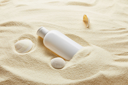 Sunblock Moisturizing Lotion In White Bottle In Sand With Seashells