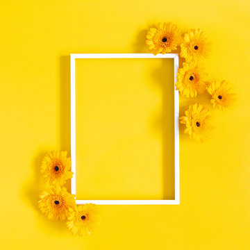 Flowers composition. Yellow gerbera flowers, photo frame on yellow background. Flat lay, top view, copy space