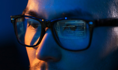 vision, hacking and technology concept - close up of hacker eyes in glasses looking at computer screen in darkness