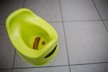 A green children's potty with feces in the toilet