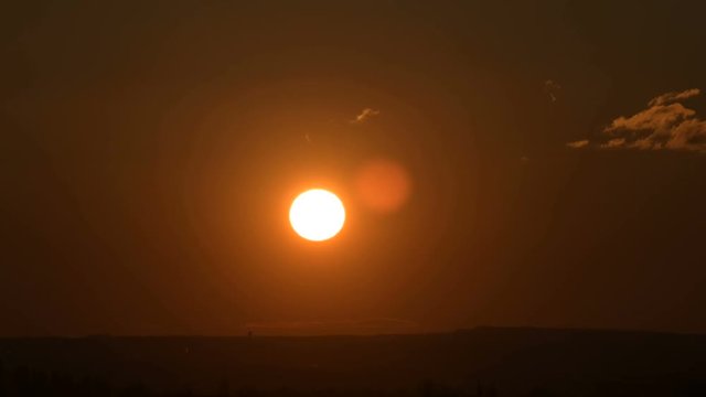 Superzoom plan timelapse sunset with a clear sky in orange tones on a flat horizon
