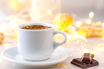 Romantic breakfast. A cup of black coffee with chocolate on a background of glowing lanterns. Postcard Design