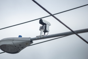 A traffic camera mounted on top of an intersection street light signal