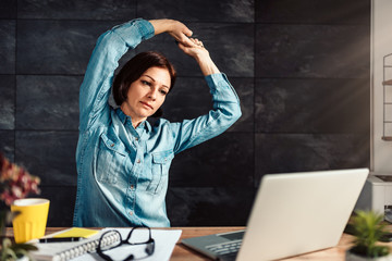Business woman stretching arms in the office