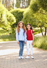 Fototapeta premium School kids stand embracing in a row outdoors, full length