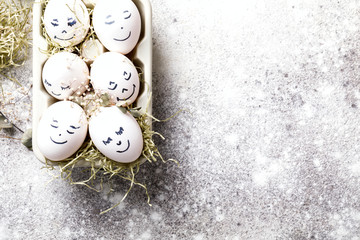 Easter holiday concept with cute handmade eggs.Funny decoration in a festive  background.Eggs with funny faces in the package.Spring mood.Copy space for Text