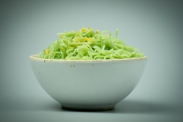 Close up of green noodle in white ceramic bowl