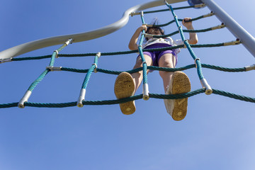 teenage girl playing with motor activity developer toys like rope wall and spider web at the playground