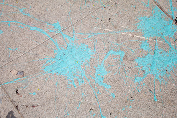 Blue paint splattered on a sidewalk