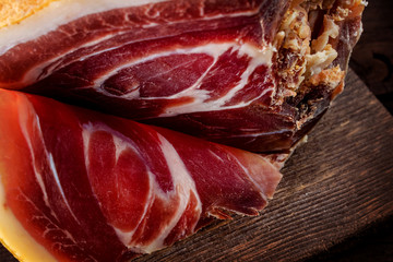 Spanish ham, bellota, jamon serrano, crudo, italian prosciutto, whole leg,  parma ham cut with a knife and lying on a wooden board. Close-up.