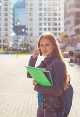 Back to school student teenager girl holding books and note books wearing backpack. Outdoor portrait of young teenager brunette girl with long hair. girl on city