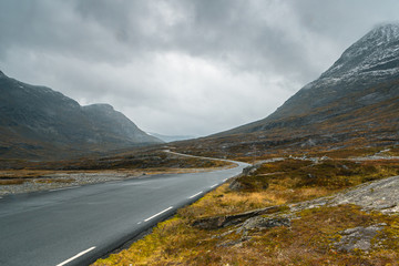 Asfaltowa, kręta, górska droga w czasie deszczu i we mgle. Norweski surowy klimat. Skaliste góry.