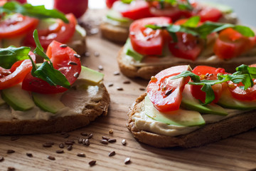 Fresh  toasts with avocado and tomatoes on wooden table 