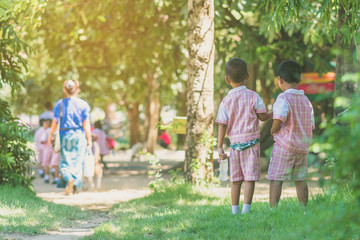 Obraz premium Kindergarten boy walk after female teacher and his friends back to class after having lunch.