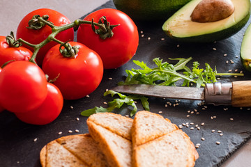 Tomatos and avocado on black table close up, colorful healthy food 