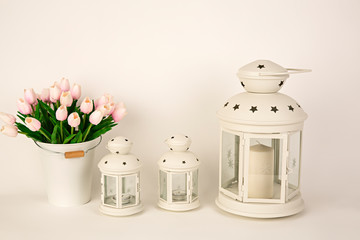 Faroles blancos con velas y macetero con tulipanes rosas.