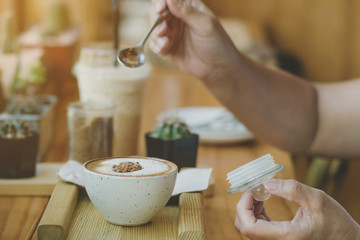 Woman pouring sugar into a white cup of coffee