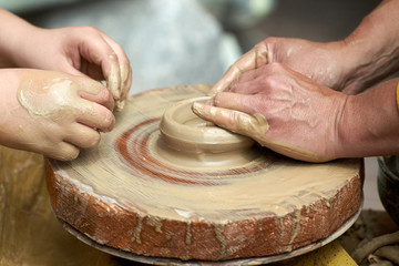 A closeup of a hand of two artisans making a jug