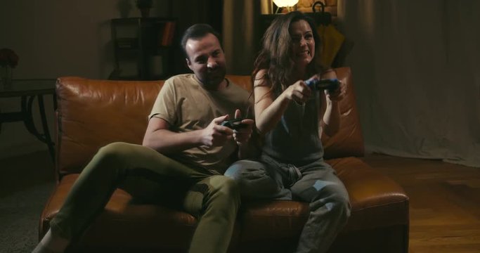 Couple enjoys playing videogame on playstation in dark room at home