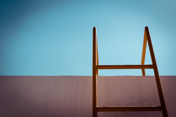 yellow metal ladder and stained wall in daylight, obstacle and success concept