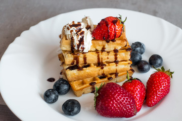  Belgian waffles with Strawberry and Blueberries on white blate close up