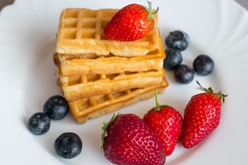  Belgian waffles with Strawberry and Blueberries on white blate close up