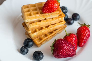  Belgian waffles with Strawberry and Blueberries on white blate close up