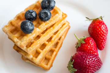  Belgian waffles with Strawberry and Blueberries on white blate close up