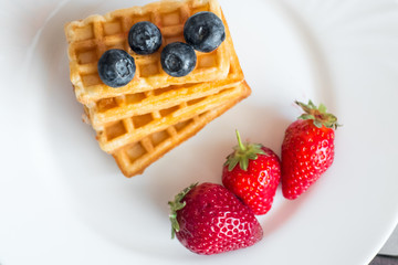  Belgian waffles with Strawberry and Blueberries on white blate close up