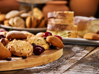 Fototapeta premium Oatmeal cookies and sand chocolate cake with cherry berry and crispy wafer rolls with cream on cutting board on wooden table in rustic style. Limitations for diabetics. Rejection of many products.