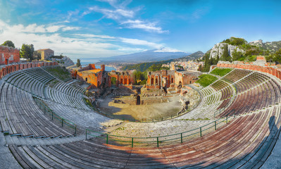 Ruins of ancient Greek theater in Taormina and Etna volcano in the background.