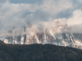 view of snowy mountain summit on cloudy day surrounded alpine forests