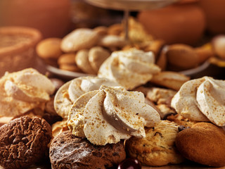 Oatmeal cookies and sand chocolate cake with cherry berry and crispy wafer rolls with cream on cutting board on wooden table in rustic style. Dessert in expensive restaurant.