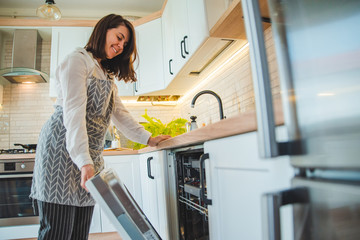 young pretty woman putting dishes in dishwasher