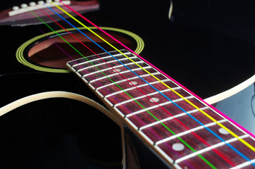 Acoustic guitar with colored luminous strings. On a black background