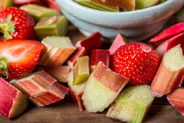 Close up of Pieces of Raw and Freshly Cut Rhubarb and Strawberries on Dark Rustic Background